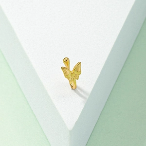 Minimalist golden butterfly fake nose ring or ear cuff on a modern geometric display