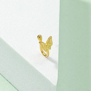 Detailed view of a gold butterfly fake nose ring on a minimalist geometric white block