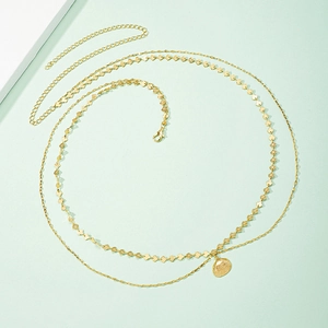 Double-layered gold waist chain with shell pendant and leafy accents on light green background