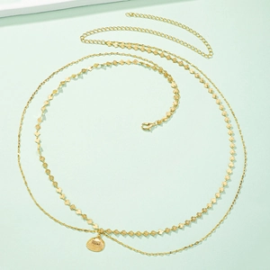 Detail of a golden double-layered waist chain with bohemian shell charms and lobster clasp