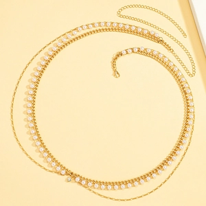 Macro view of a gold chain waist belt with layered pearls and a rhinestone charm