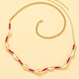 Detail of bohemian gold waist chain with pink beads and natural cowrie shell pendants