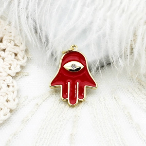 Detailed view of red enamel Hamsa hand pendant with evil eye and gold plating