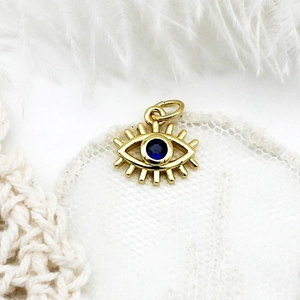 18K gold plated evil eye pendant with deep blue zircon stone on white lace background