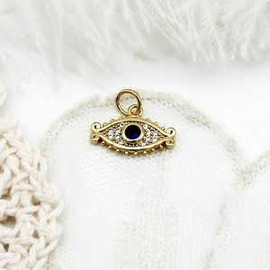 Macro shot of micro-pave evil eye pendant in 18K gold plating with blue crystal
