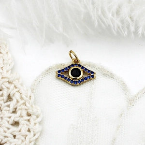 Detail of 18K gold evil eye charm with blue micro-pave crystals and black center stone
