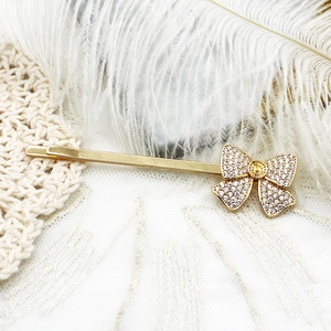 Vue macro d'une barrette à cheveux nœud dorée 18K et cristaux sur dentelle élégante