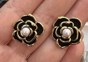 Dettaglio degli orecchini a camelia nera con placcatura in oro e perla bianca