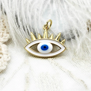 Vista macro del colgante de ojo turco chapado en oro 18K con esmalte azul sobre plumas blancas