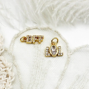 Détail de pendentifs BFF et LOL dorés 18K avec zircons posés sur de la dentelle