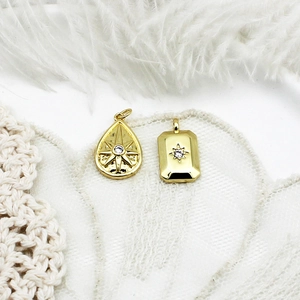 Detailed view of 18K gold plated celestial star and moon charms on white feathers
