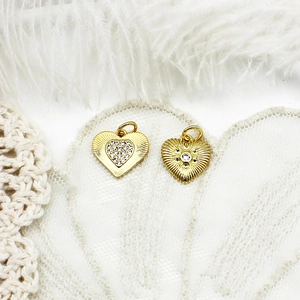 Macro shot of 18K gold plated heart pendants with micro-pave crystals on white lace