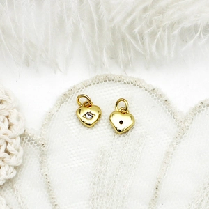 Detailed view of 18K gold heart pendant with zircon on feather and lace background