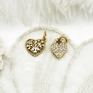 Macro detail of 18K gold heart charms with tree of life design and clear zircon inlay