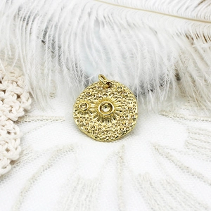 Detail of 18K gold plated celestial coin pendant with star and sun textured patterns
