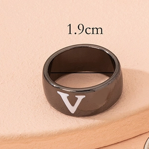 Macro detail of black enamel wide band ring featuring a bold white letter V design