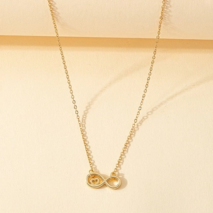 Détail du pendentif infini doré avec cœur sur chaîne fine, fond beige texturé élégant