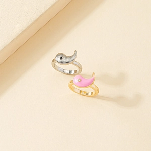 Close-up of dolphin couple rings in silver with texture and pink enamel finish