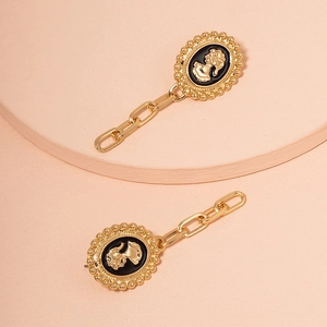 Macro detail of retro gold cameo earrings with black enamel and portrait relief