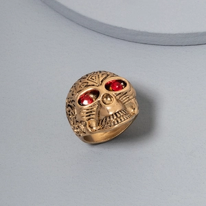 Macro view of vintage gold skull ring with engraved textures and red rhinestone eyes