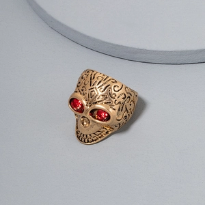 Macro shot of vintage gold skull ring featuring detailed carvings and red rhinestone eyes