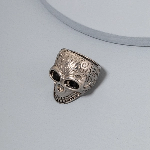 Detail of a punk skull ring with black rhinestone eyes and silver scrolled engravings