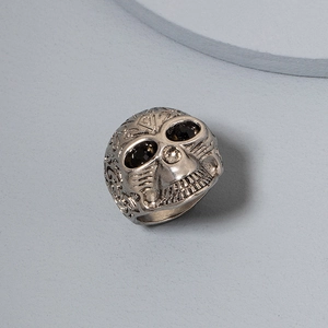 Detailed close-up of a punk skull ring with vine patterns and black gemstone eyes