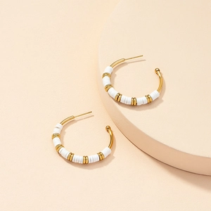 Detail of C-shaped golden hoop earrings with white round beads in Bohemian style