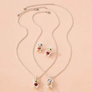 Cute astronaut jewelry set with heart and flower pendants on pink background