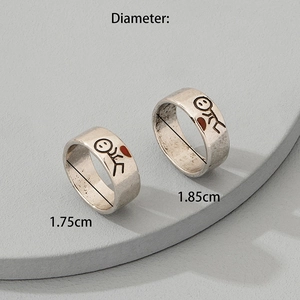 Retro silver couple rings featuring stickman patterns and red hearts on grey display