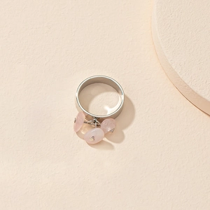 Détail d'une bague argentée avec trois pierres roses irrégulières en pendentif