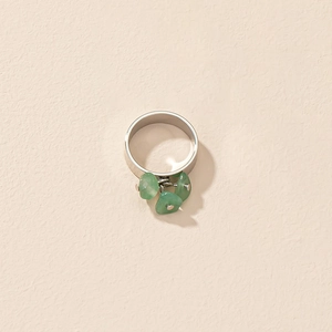 Détail d'une bague argentée avec trois breloques pendantes en pierre naturelle verte