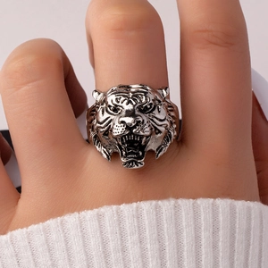 Close-up of a vintage silver tiger head ring with detailed texture on a person's finger