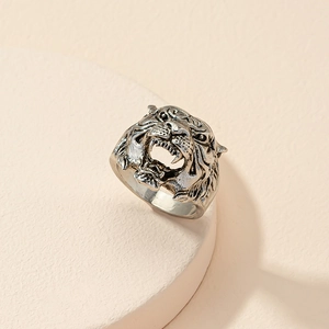 Macro shot of retro silver tiger head ring with realistic 3D engraving on a beige stand
