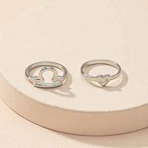 Detail of silver Libra zodiac sign and heart ring set with ME engraving for couples
