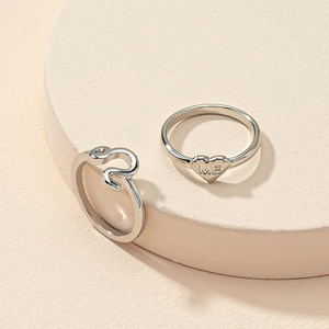 Detail of silver heart ring with ME engraving and minimalist wavy band on a round display
