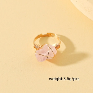 Dettaglio di pietra in cristallo rosa avvolta in filo d'oro su anello regolabile