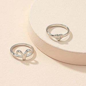 Detail view of silver rings featuring heart shape with ME engraving and zodiac symbol