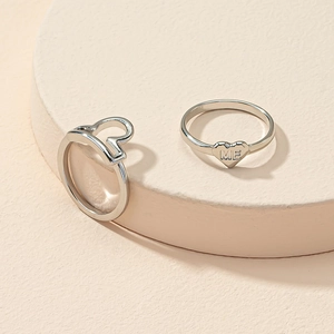Detail of silver heart ring set with ME engraving on a soft beige display pedestal