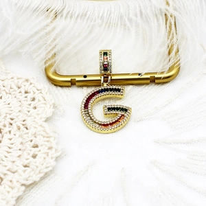Détail du pendentif lettre G plaqué or avec des pierres de zircone multicolores