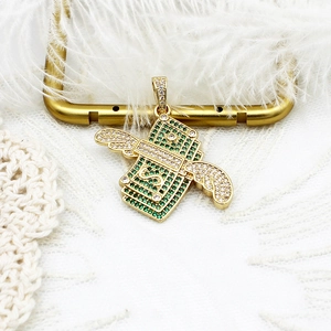 Vue macro détaillée du pendentif dollar doré avec ailes et micro-zircones vertes