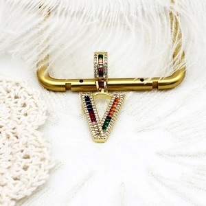 Gros plan détaillé du pendentif en V doré avec pierres multicolores et pavé de diamants