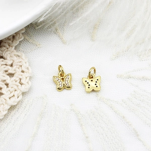 Detailed macro view of butterfly-shaped charms with micro-pave zircons and golden finish