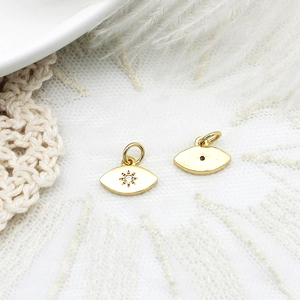 Macro detail of gold eye-shaped charm pendants showing front and back craftsmanship