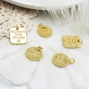 Detail of 18K gold plated square and round lucky charms with engraved inscriptions