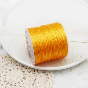 Close-up of golden elastic jewelry thread for DIY beading on a decorative white dish