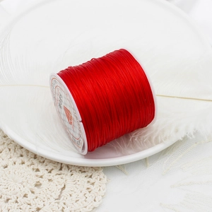 Red elastic crystal string for DIY jewelry making on white spool with decorative feather