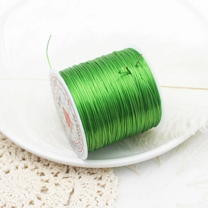 Vibrant green elastic cord for jewelry making on white spool with decorative feather