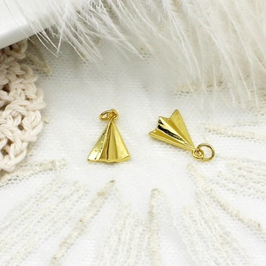 Close-up of gold paper plane charms with zircon inlay for DIY jewelry and necklaces