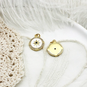 Detail of 18K gold plated compass star charms with white enamel and blue zircon stones